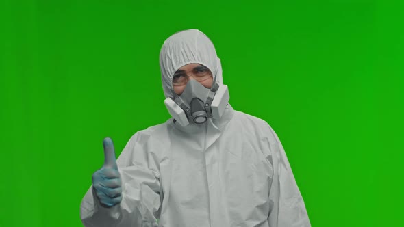 Portrait of a Man in a Protective Suit Glasses and a Mask Looks at the Camera and Shows a Thumbs Up