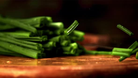 Super Slow Motion Pieces of Green Onion Fall on the Table