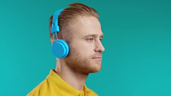 Handsome Young Teenager Listening to Music with Blue Headphones Guy Having Fun Smiling in Studio on