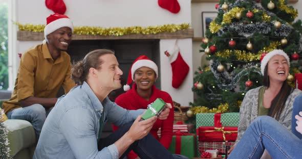 Happy diverse group of friends sharing with presents at christmas time