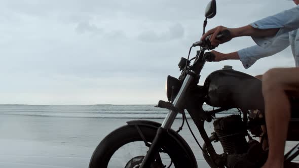 Man in Riding Motorcycle on Beach. Vintage Motorbike on Beach Sunset on Bali. Young Hipster Male