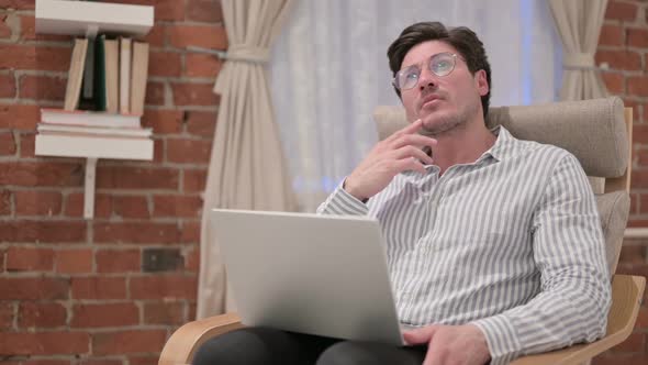 Middle Aged Man with Laptop Thinking on Sofa