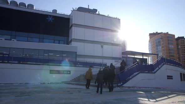 Pedestrians Walk to Stadium Building with Stairs in Winter