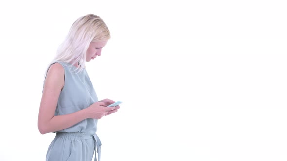 Profile View of Happy Young Blonde Woman Using Phone While Waiting