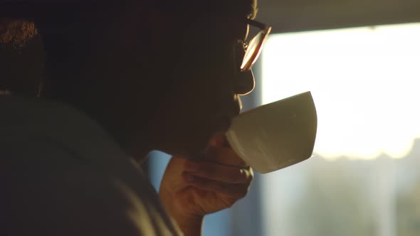 Close Up of Handsome Afro Man in Bathrobe Drinking Coffee While Looking Out Window in Morning