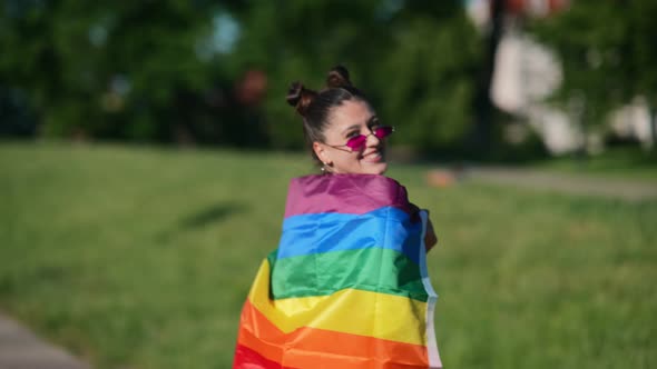 Young Woman with Lgbt Pride Flag Walking in the Park