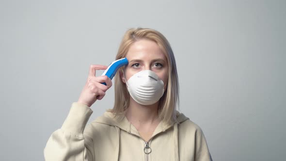 Female in the mask measures temperature