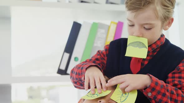 Boy as business executive placing sticky notes over colleagues eyes