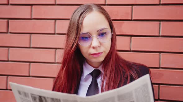 Young Woman Reading Newspaper on Street