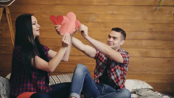 Enamored Man and Woman are Playing with Cut out Hearts of Red Color