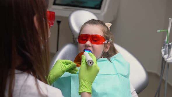 Little Cute Girl at Dentist Clinic Gets Dental Treatment to Fill a Cavity in a Tooth