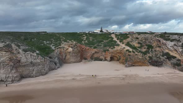 Long aerial shot flying backwards from a coastline of rugged cliffs underneath a dramatic sky, over