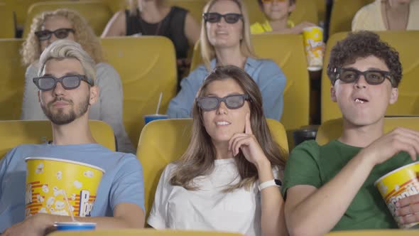 Group of People in 3d Glasses Watching Movie As Unrecognizable Man Passing at Front Preventing Them