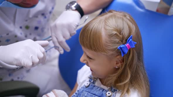 Little girl sitting in dentists chair. Pretty kid opens her mouth to the stomatologist.