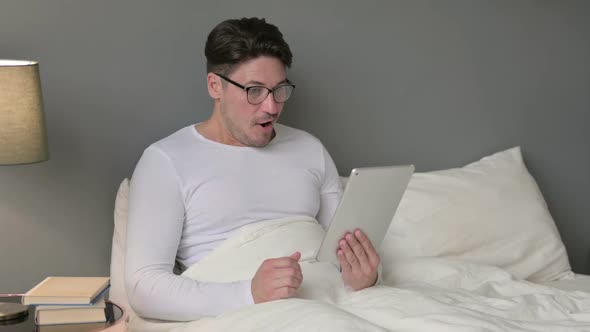 Excited Middle Aged Man Celebrating on Tablet in Bed