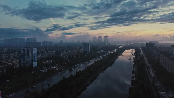 Aerial View of a Big City After Rain Cloudy Sky Smog Riverscape Next to Buildings and Avenue with