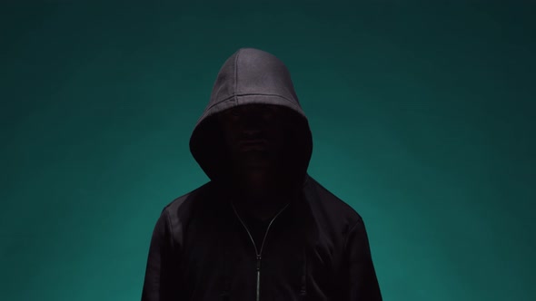 Portrait of computer hacker in hoodie. Obscured dark face.