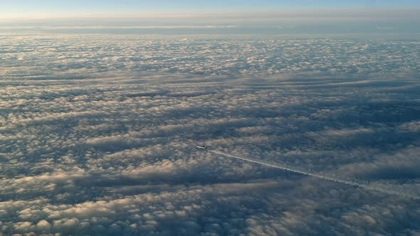 Incredible view from the cockpit of an airplane flying high above the clouds leaving a long white co