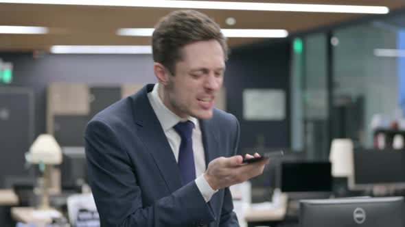 Angry Businessman Talking on Smartphone in Office