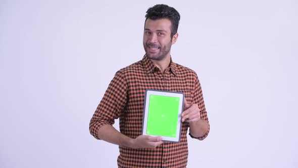 Happy Bearded Persian Hipster Man Showing Digital Tablet and Looking Surprised