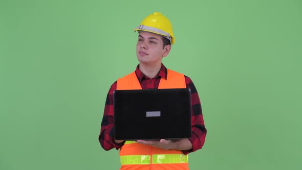 Happy Young Multi Ethnic Man Construction Worker Thinking While Using Laptop