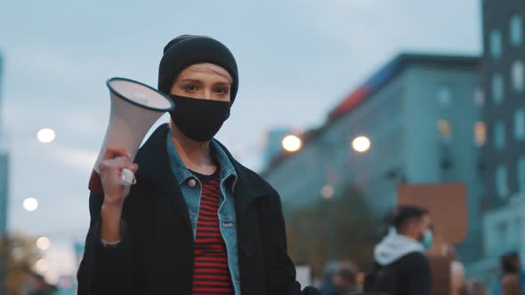 Woman with Face Mask Holding Megaphone and Rainbow Flag. Demonstration Against Dicrimination 