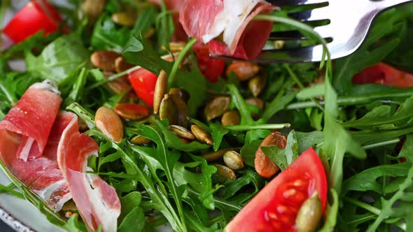 Eating salad. Healthy italian salad with tomatoes, arugala and hamon. Fresh salad with hamon.