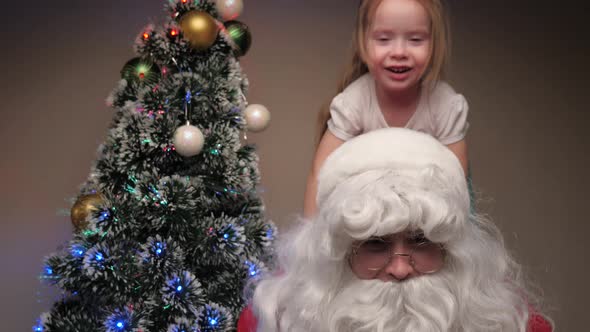 Child and Santa Claus Are Playing Together a Little Girl Is Sitting on Back of Santa Claus