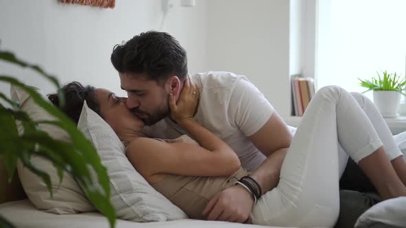 Young Woman and Bearded Man are Kissing While Lying on Bed in Home Bedroom Spbd