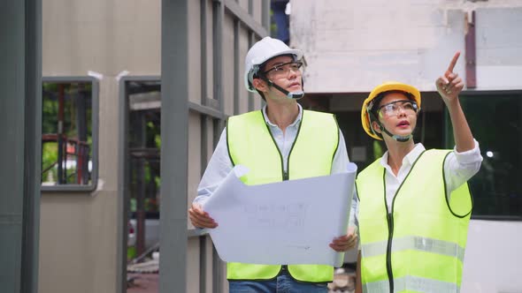 Asian colleague workers people wearing protective safety helmet and glasses onsite of architecture.