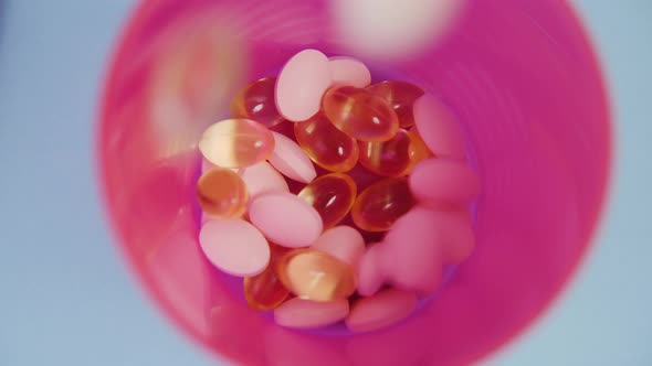 Pink and Yellow Tablets Fall Into a Plastic