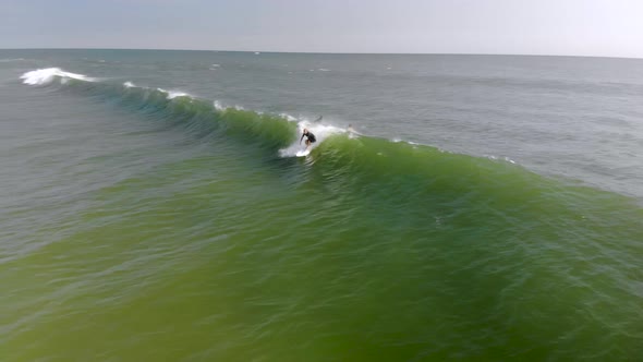 Epic drone tracking shot of surfer riding a wave.