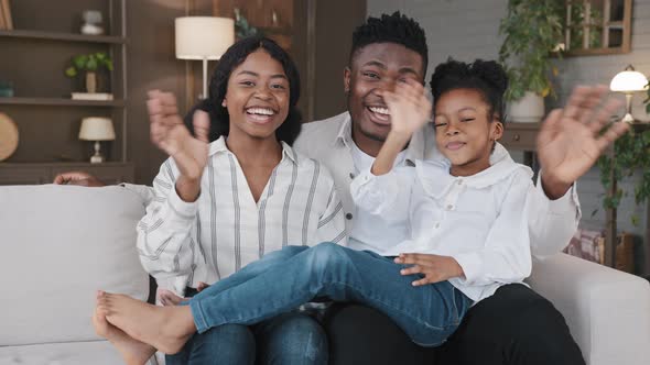 African Family with Daughter Sitting at Home Waving Hands Greeting Look at Camera Talking at Webcam