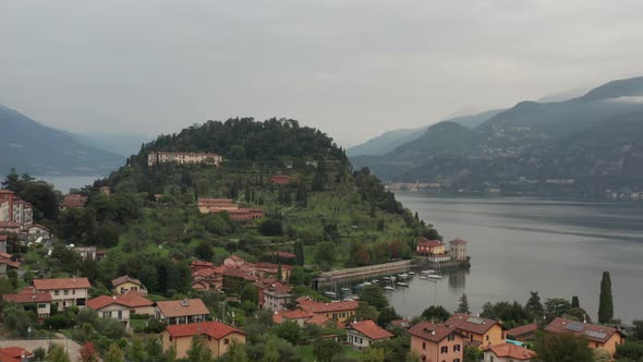 Aerial view of the city of Bellagio with a green mountain filled with buildings in the background