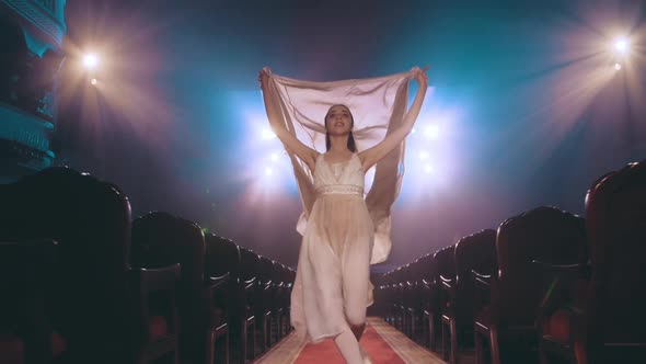 The muse of art. A young girl runs through the theater with a huge silk fabric. Ballet