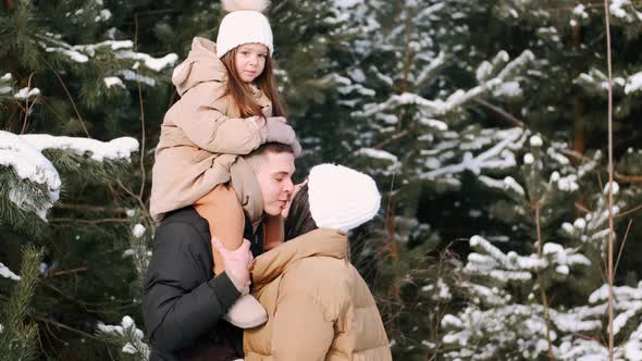 Parents with Daughter Walking in Forest in Winter