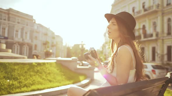 Young Beautiful Girl in Hat Photographing in City Park