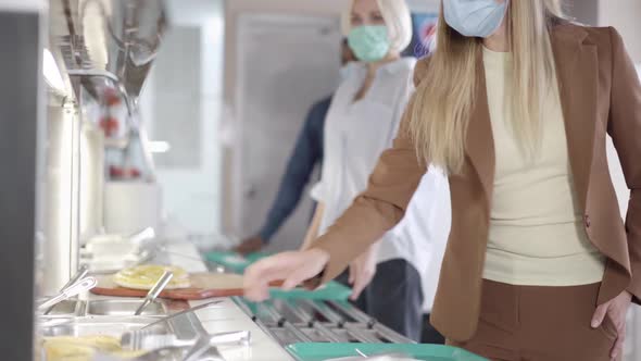 Queue of Multiethnic People in Covid19 Face Masks Choosing Food in Lunchroom