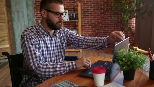 Confident Hipster Man in Wheelchair Finishes Working on Laptop Closes It and Drives Away