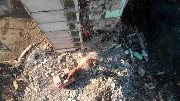 An Excavator Tractor Digs the Concrete Ruins of a Collapsed House with a Bucket