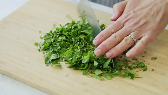 Woman cutting parsley on wooden board