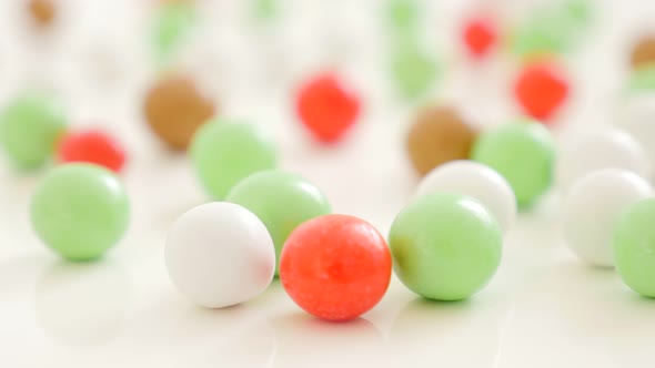 Many colorful round candies on white reflective surface slow tilting 4K 3840X2160 UltraHD video - Ar