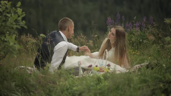 Groom with Bride Having a Picnic on a Mountain Hills. Wedding Couple. Family