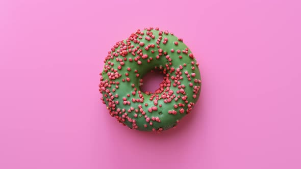 Appetizing Bright Fresh Doughnut with Green Icing Rotating Isolated on Pink