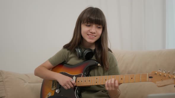 Cheerful Teen Girl Learns to Play the Guitar