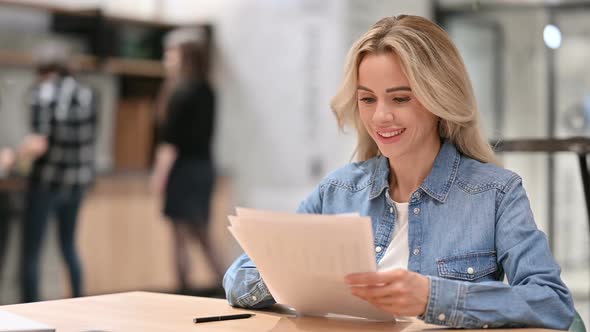 Excited Woman Celebrating Success on Documents