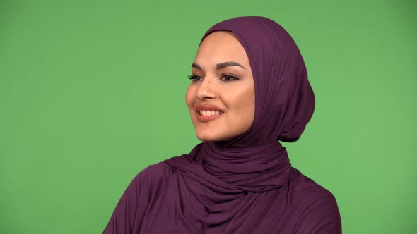A Young Beautiful Muslim Woman Looks Around with a Smile  Closeup  Green Screen Background