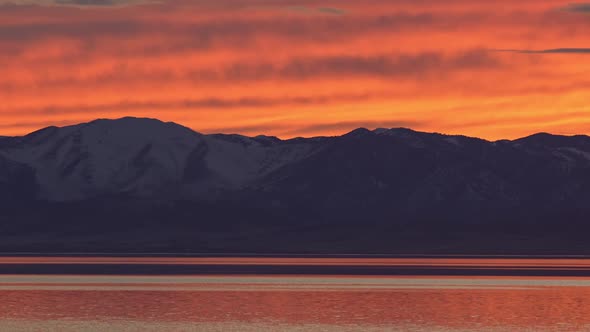 Fiery sunset over mountains reflecting in lake