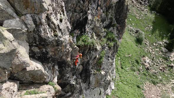 Woman Athlette Climbing on the High Rock in the Mountains