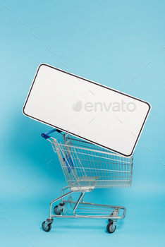 shopping cart with huge template of mobile phone on blue background